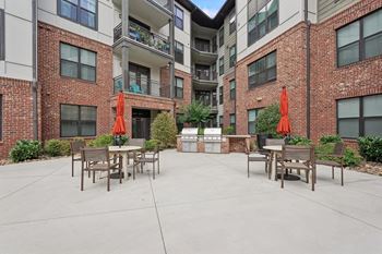 A courtyard with tables and chairs surrounded by brick buildings.